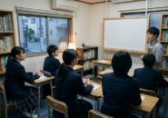 塾の教室で講師の説明を聞く中学生たち