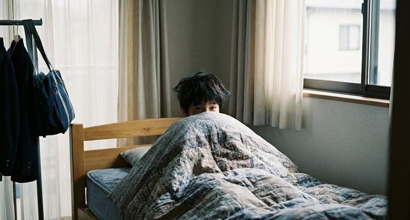 朝、布団をかぶって起きられない男子中学生