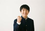 白背景でガッツポーズをする笑顔の男子中学生