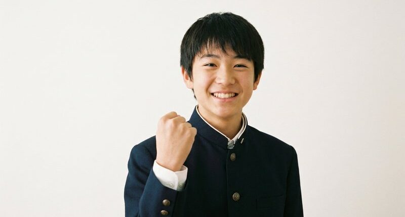 白背景でガッツポーズをする笑顔の男子中学生