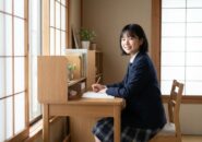 机の前で笑顔を見せる女子中学生